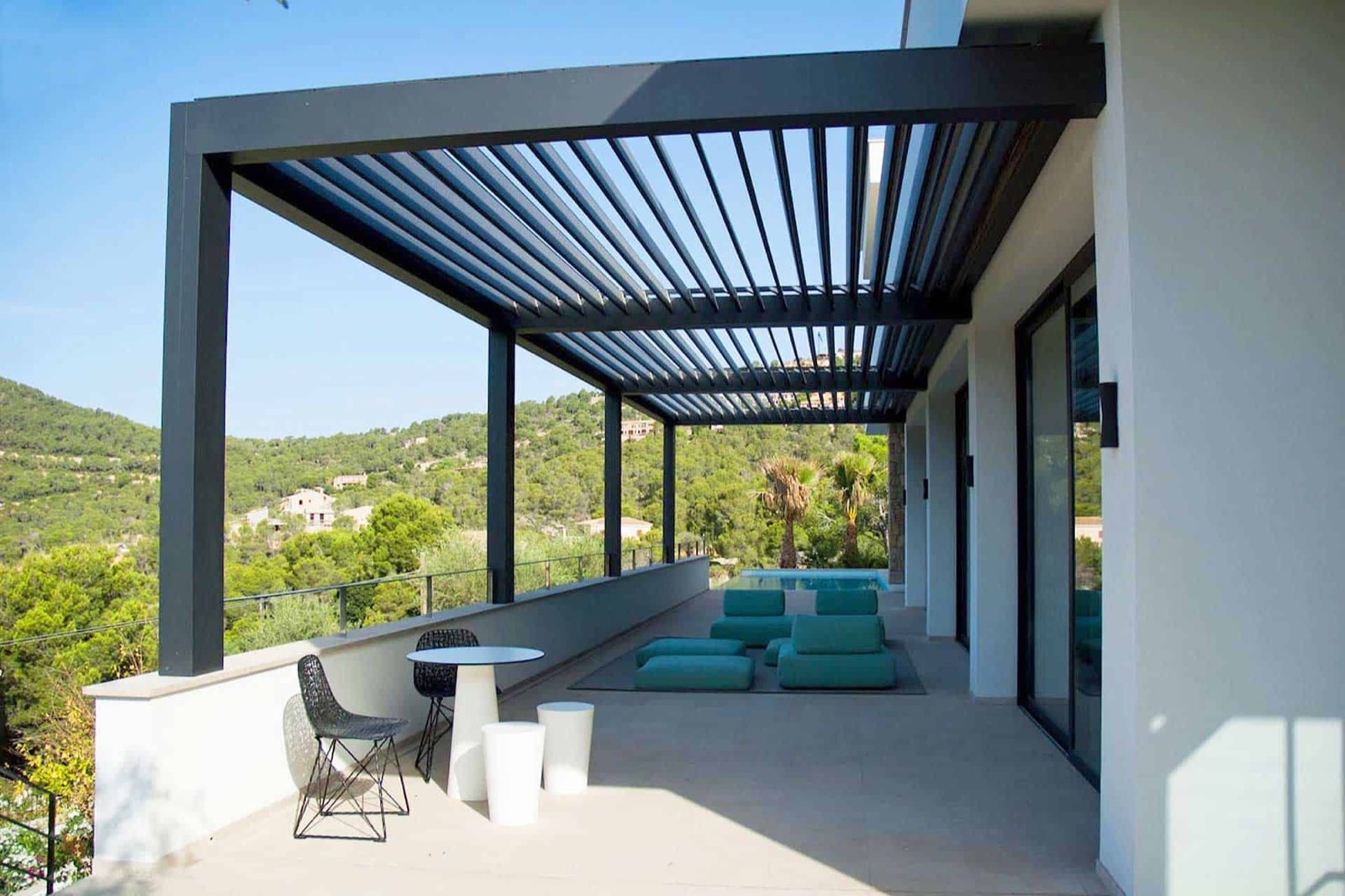 Pérgola bioclimática SEESKY-BIO adosada a una vivienda, con las lamas orientables abiertas sobre una terraza con vistas (imagen del fabricante)